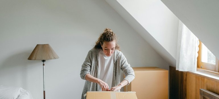 Calm woman unpacking big box in light by following the attic storage ideas guide