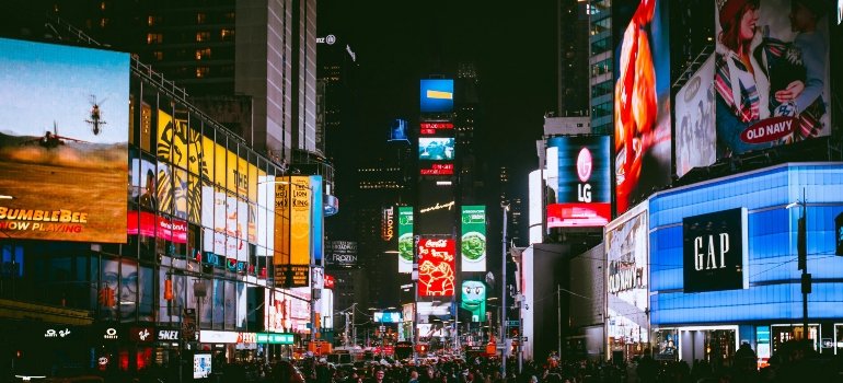 Bright Times Square at night with glowing billboards lighting up the crowd.