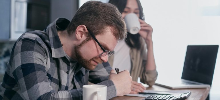 Man in Gray and Black Plaid Dress Shirt Wearing Black Framed Eyeglasses Holding White Ceramic Mug