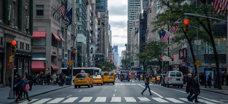 Street view of Manhattan with yellow taxis, buildings, and flags, tied to myths about moving to Manhattan conversations.