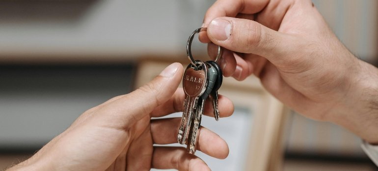Close-up of hands exchanging keys during a home move.