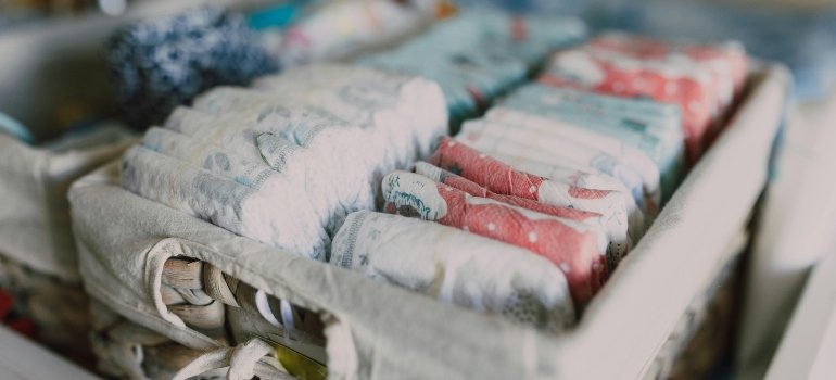 Storage tips for expecting parents shown with organized diapers neatly arranged in a woven basket.