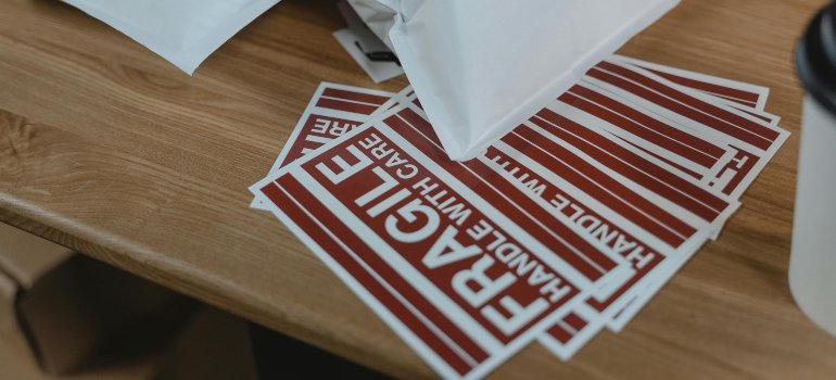 “Fragile: Handle with Care” stickers and mailers on a wooden desk, ready for packaging or storage.