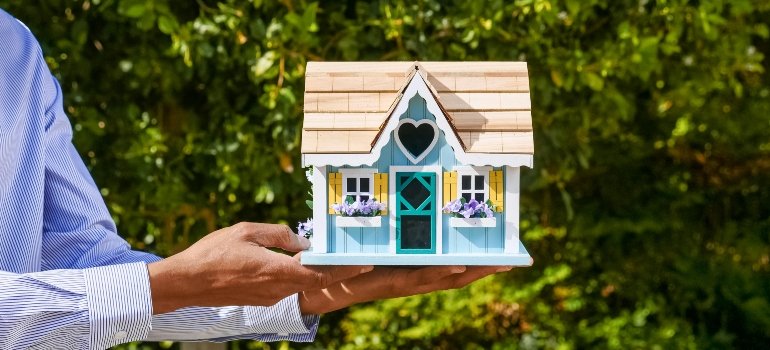 A man holding a small house model in his hands