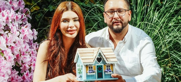 a man and a woman holding a house model their hands