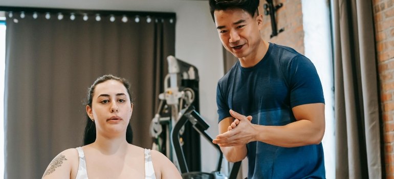 Supportive Personal Trainer Helping a Woman at the Gym