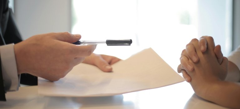Hands holding a pen and paper during a discussion about Bronx Storage Unit Restrictions.
