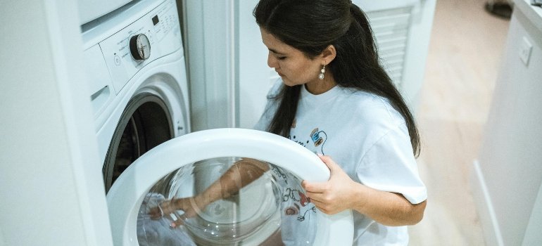 A Woman Wearing a White Shirt Doing a Laundry Kneeling