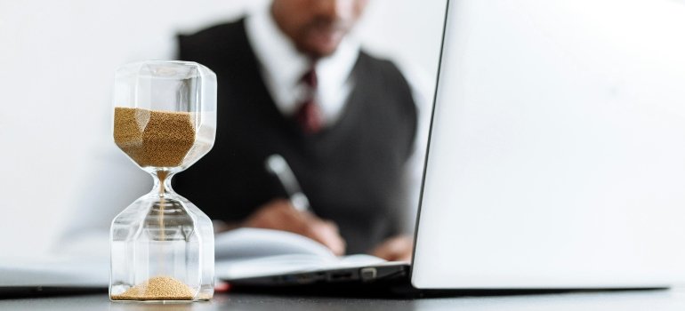 Hourglass on desk beside laptop showing focus on Business Storage in Manhattan planning.