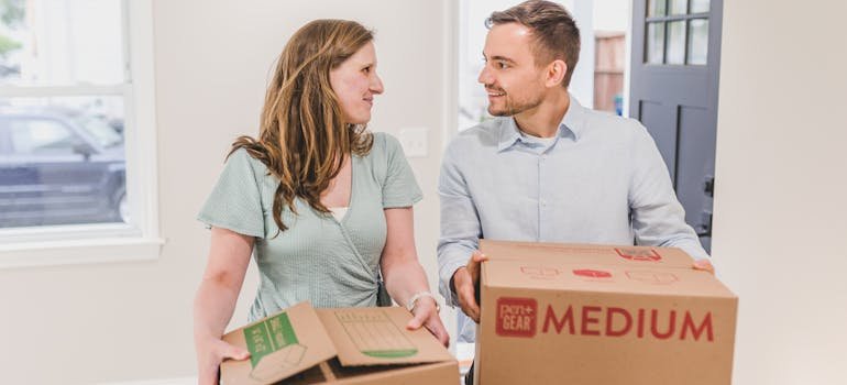 A couple holding moving boxes