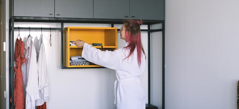 A woman organizing a closet by following NYC small apartment survival guide