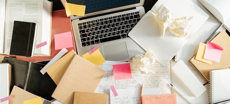 A laptop and notebooks with college dorm checklist