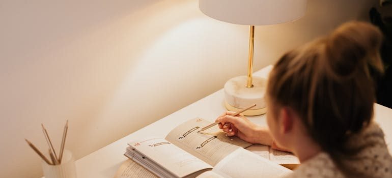A woman at the desk writing a college dorm checklist