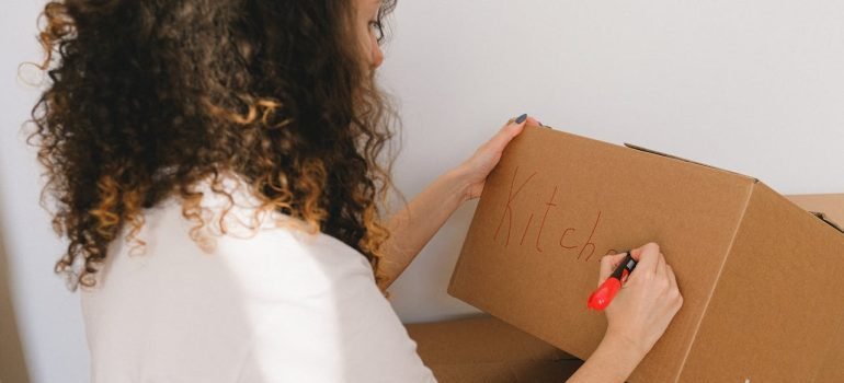 A person labeling a moving box