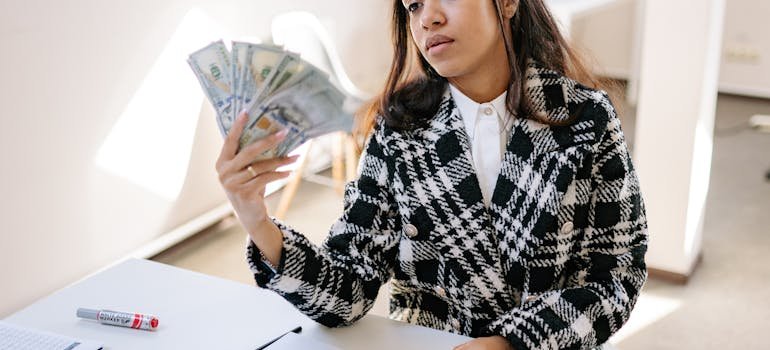 A woman counting dollar bills and thinking indoor vs outdoor car storage