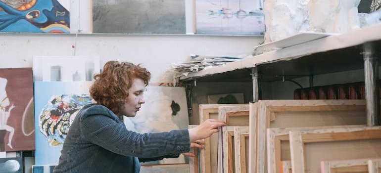 A woman looking at the paintings and thinking how NYC artists can use storage for large canvases
