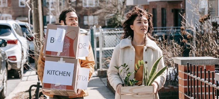 A couple holding moving boxes and talking about life events that call for long term storage