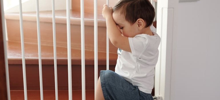 A baby trying to climb a gate for the stairs