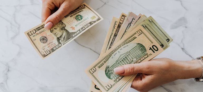 A person counting dollar bills and thinking why Tribeca residents are choosing Bedford Park