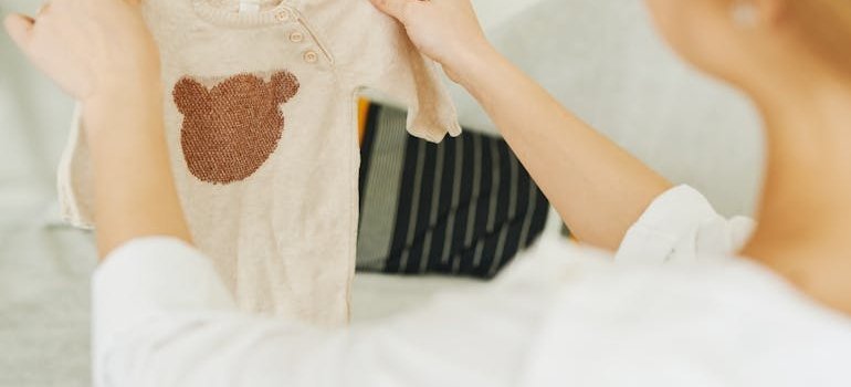 A person holding baby clothes and thinking about storage for new parents in small apartments