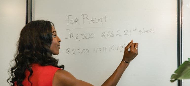 A woman using board to calculate how business storage beats renting a bigger office