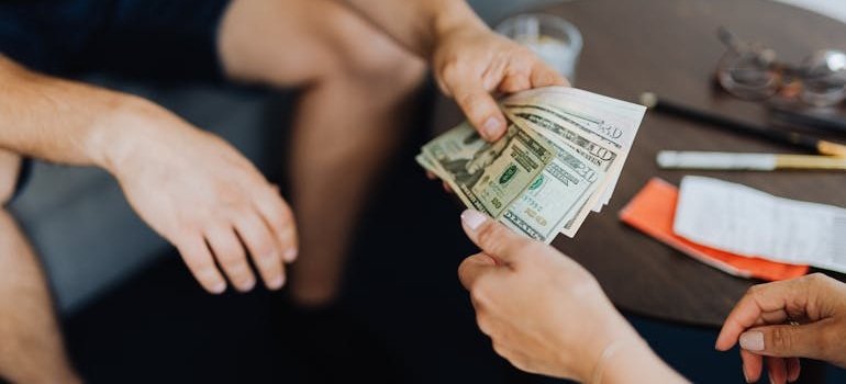 Two people who are sharing storage space in NYC counting dollar bills