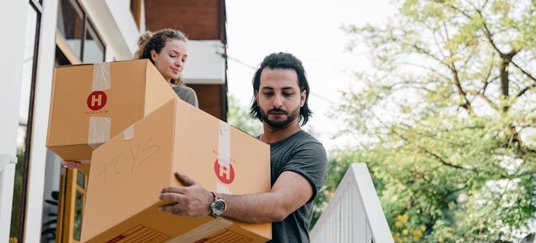 A couple carrying boxes and moving to the Bronx with no elevator