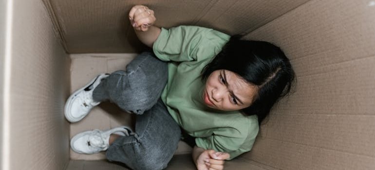 A woman in the box thinking about signs your Manhattan apartment needs extra storage
