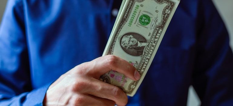 A person holding dollar bills and thinking about climate controlled storage vs standard storage