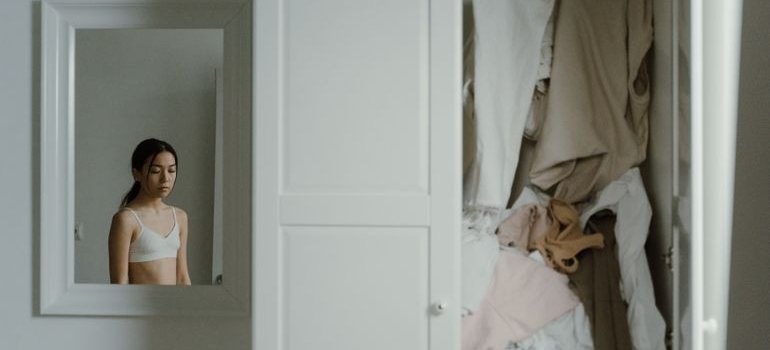 A woman next to the full closet thinking about storage unit instead of a bigger apartment